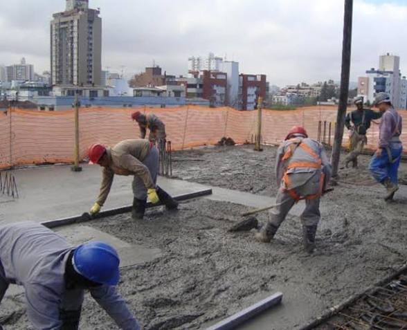 Equipe aplicando e nivelando concreto usinado em laje